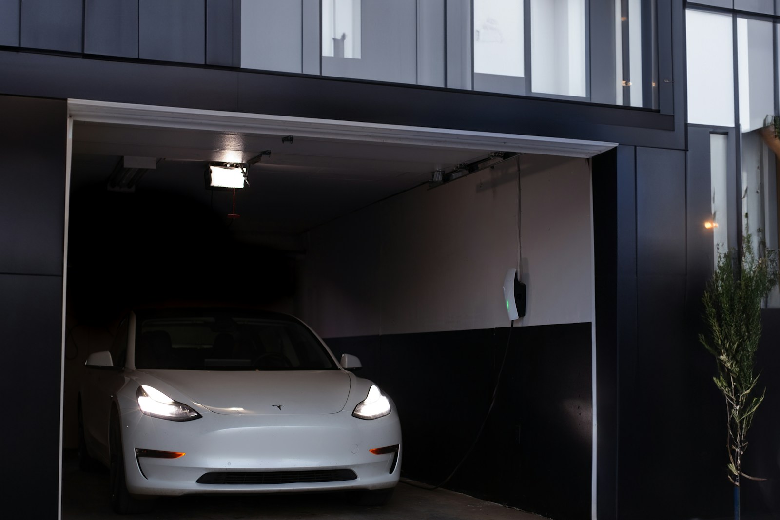 White electric car parked and charging inside a residential garage