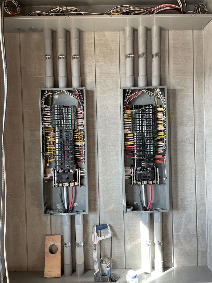 Twin 200-amp electrical panels installed with conduit runs in a new home